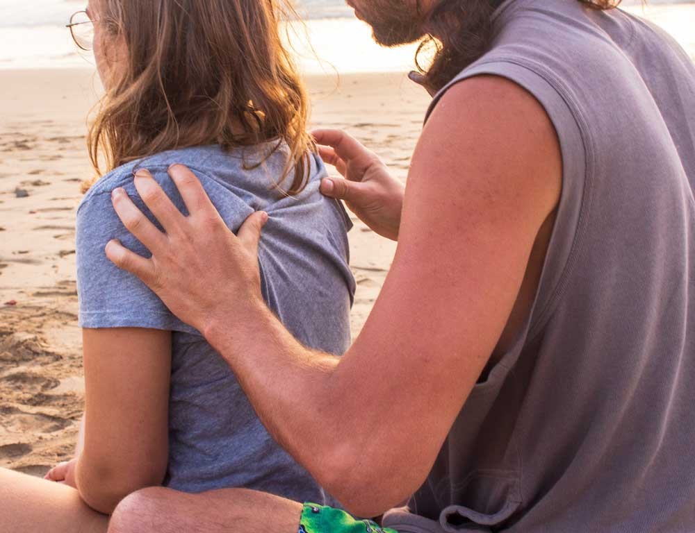 hombre dando un masaje a una chica en la playa